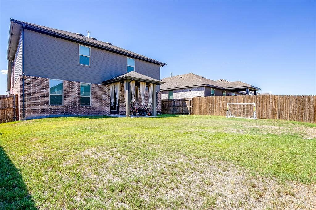 Expansive backyard featuring a wood privacy fence and a covered patio with columns