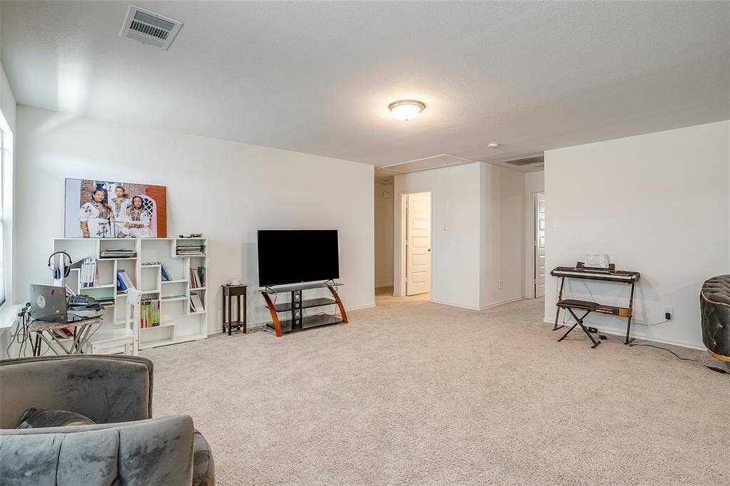 Expansive carpeted room with multiple entryways, white walls, and a flush-mount ceiling light