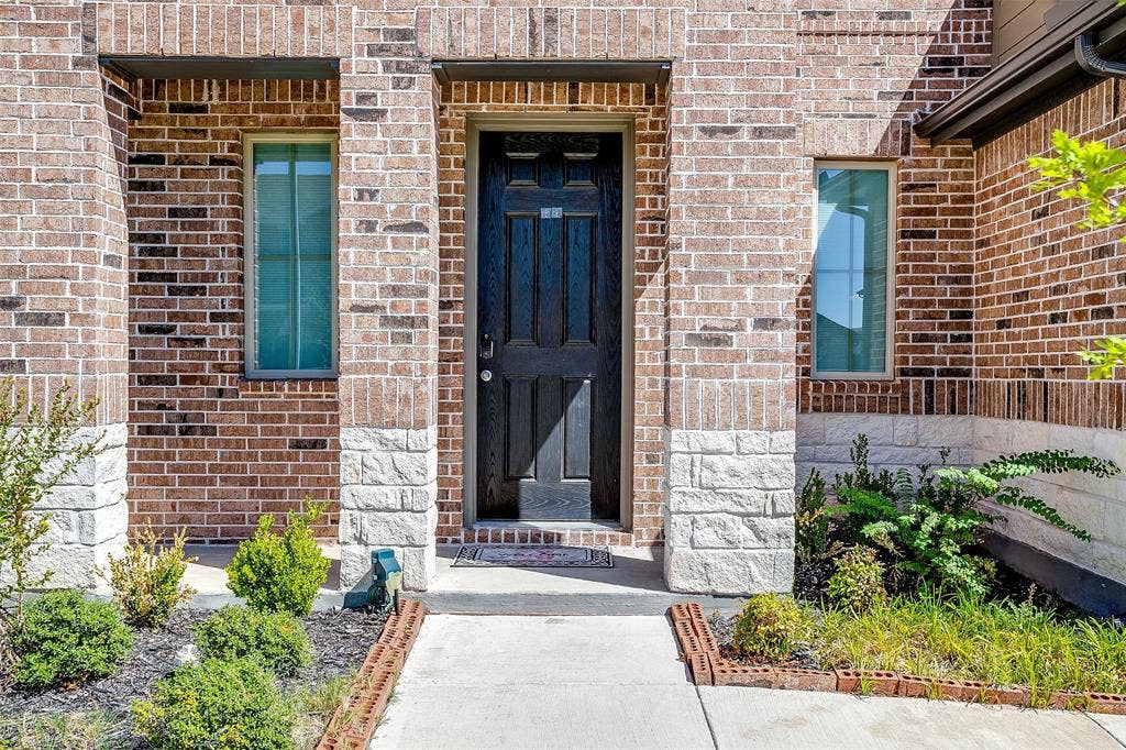 Brick exterior with stone accents, a dark wood-finish entry door, and slender windows