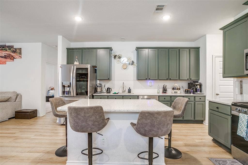 Kitchen featuring a central island with countertop seating, wood-finish flooring, recessed lighting, and green shaker-style cabinetry