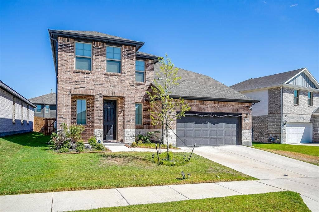 Two-story brick facade with stone accents, a two-car garage, and a concrete driveway