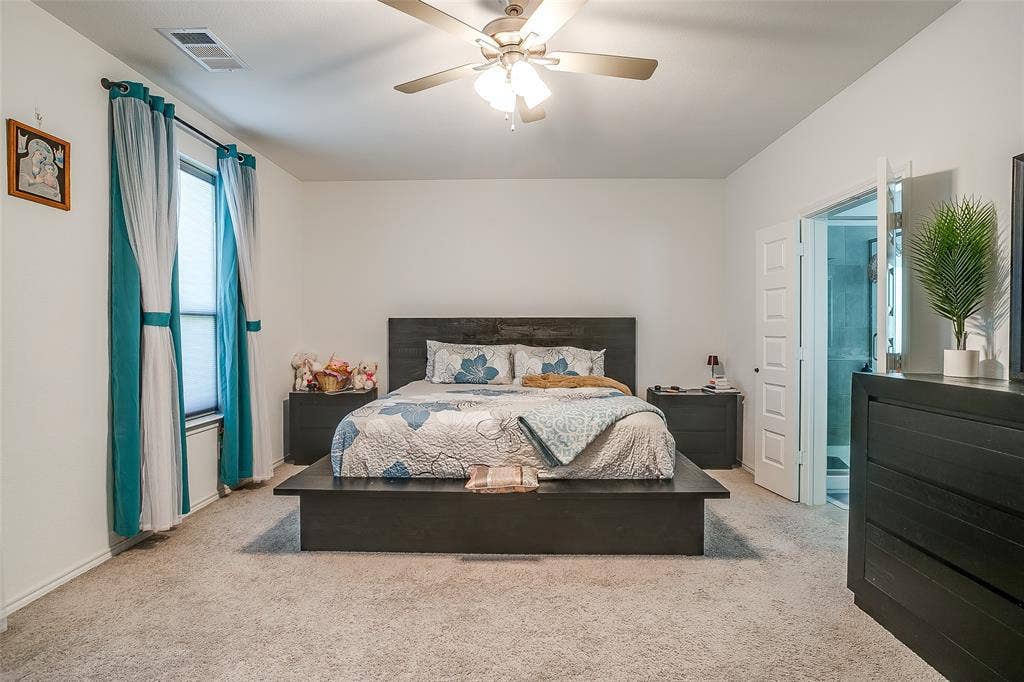 Carpeted room featuring a ceiling fan, a window with blinds, and an open doorway revealing a shower