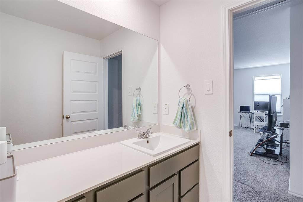 Single vanity with a rectangular undermount sink, chrome faucet, and expansive wall-mounted mirror