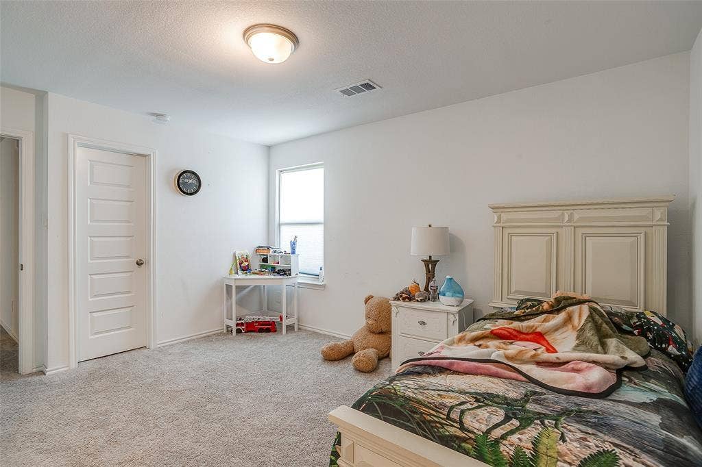 Neutral-toned wall-to-wall carpeting, white five-panel interior door, single window with blinds, and flush-mount ceiling light fixture