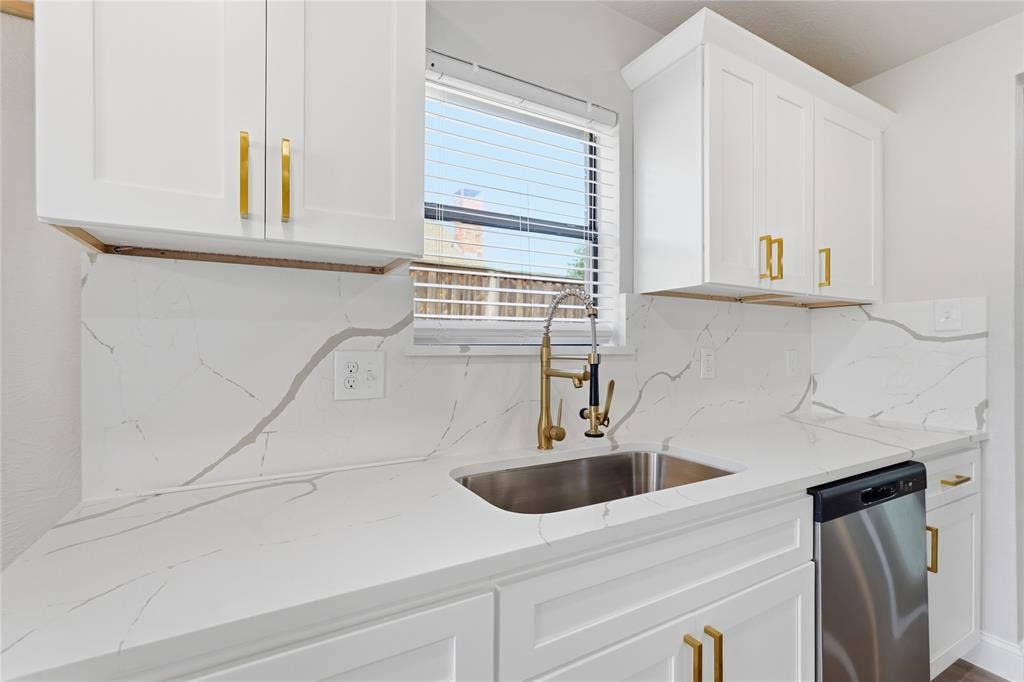 5514 Round Rock Road, Garland, TX 75044 White cabinetry with gold-finish hardware, stainless steel sink, gold-finish faucet, white patterned countertops, and a stainless steel dishwasher