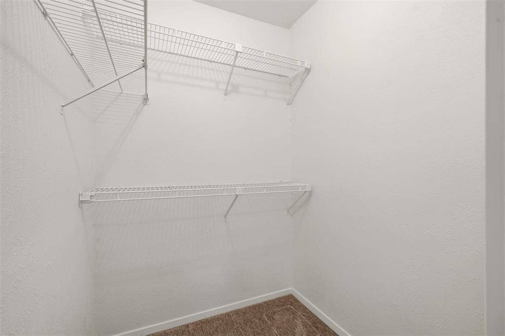 White wire shelving system with multiple tiers, textured white walls, and carpeting