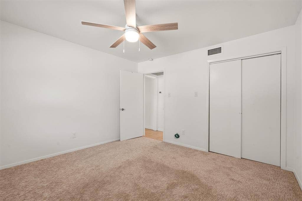 Carpeted flooring with a ceiling fan light fixture and sliding closet doors