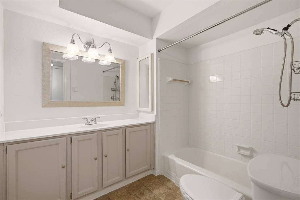 Spa-inspired primary bathroom featuring a dual-sink vanity with ample storage, framed mirror with integrated lighting, and a spacious walk-in shower with glass enclosure and rainfall showerhead