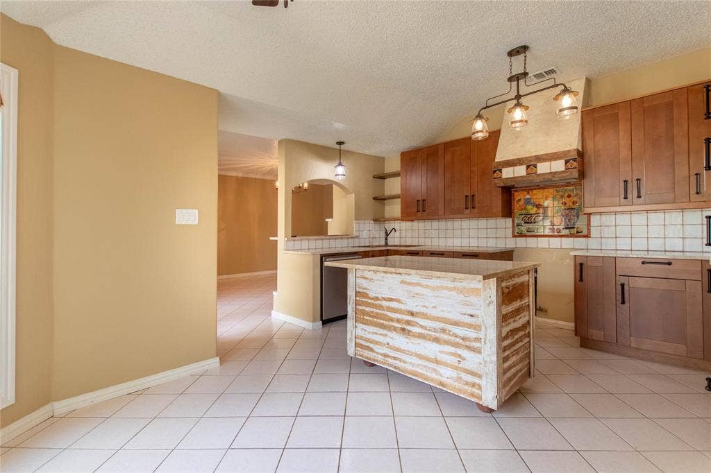 Kitchen featuring wood cabinetry, a decorative range hood, and a functional island