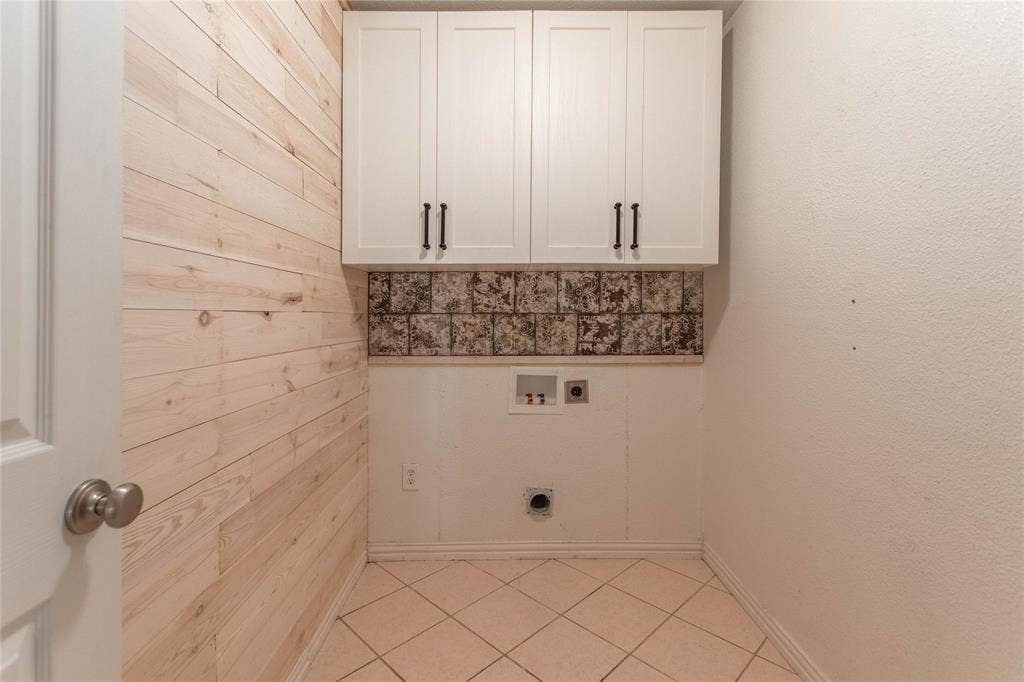 Light wood-paneled accent wall with upper white cabinetry and dark hardware