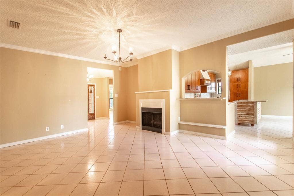 Tile flooring throughout, a central chandelier, and a built-in fireplace with a mantel