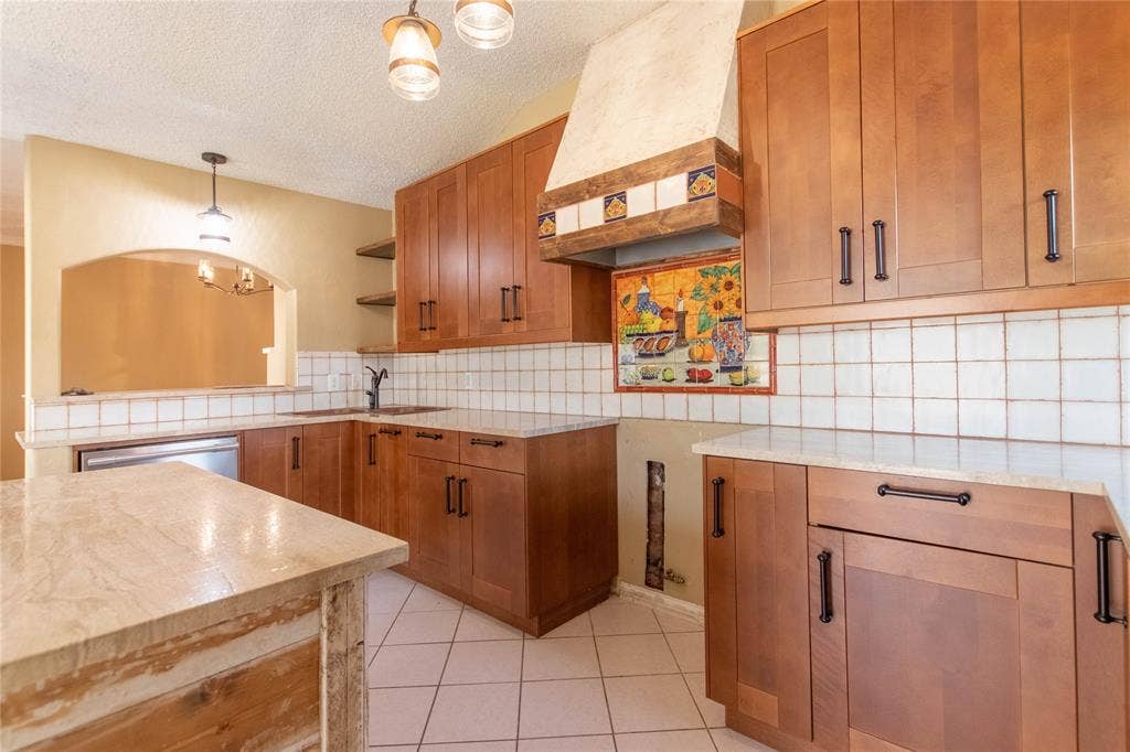 Spacious kitchen featuring rich wood cabinetry with ample storage, white subway tile backsplash, light-filled countertops, and stainless steel appliances