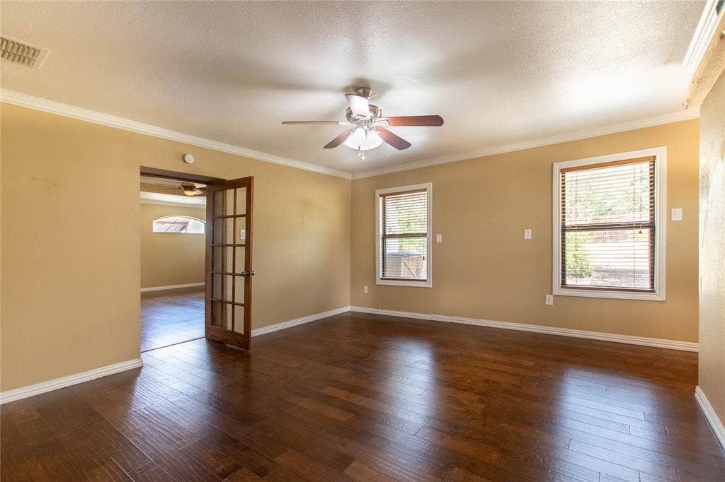 Hardwood-style flooring throughout, crown molding, and a ceiling fan with integrated lighting