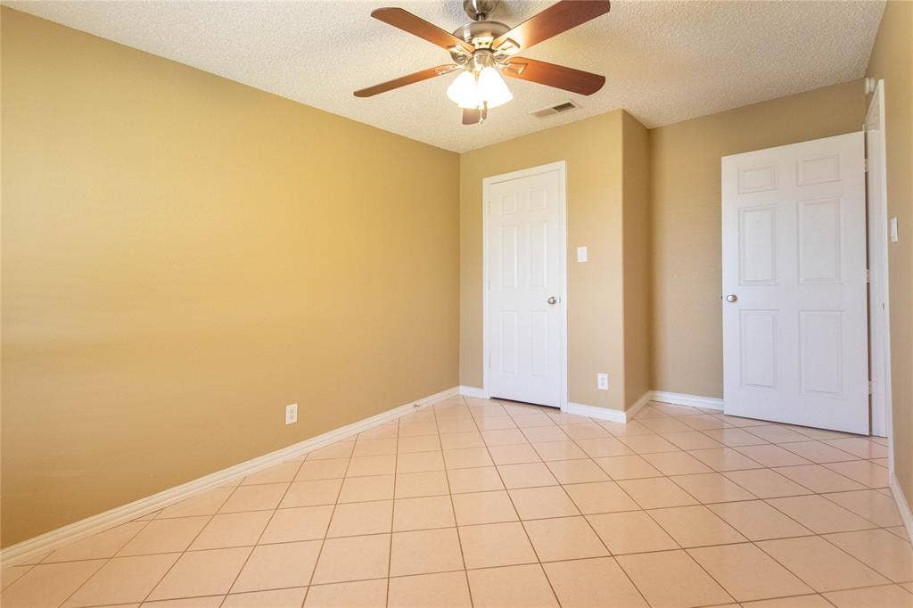 Tiled flooring, ceiling fan with light fixture, and two panel doors