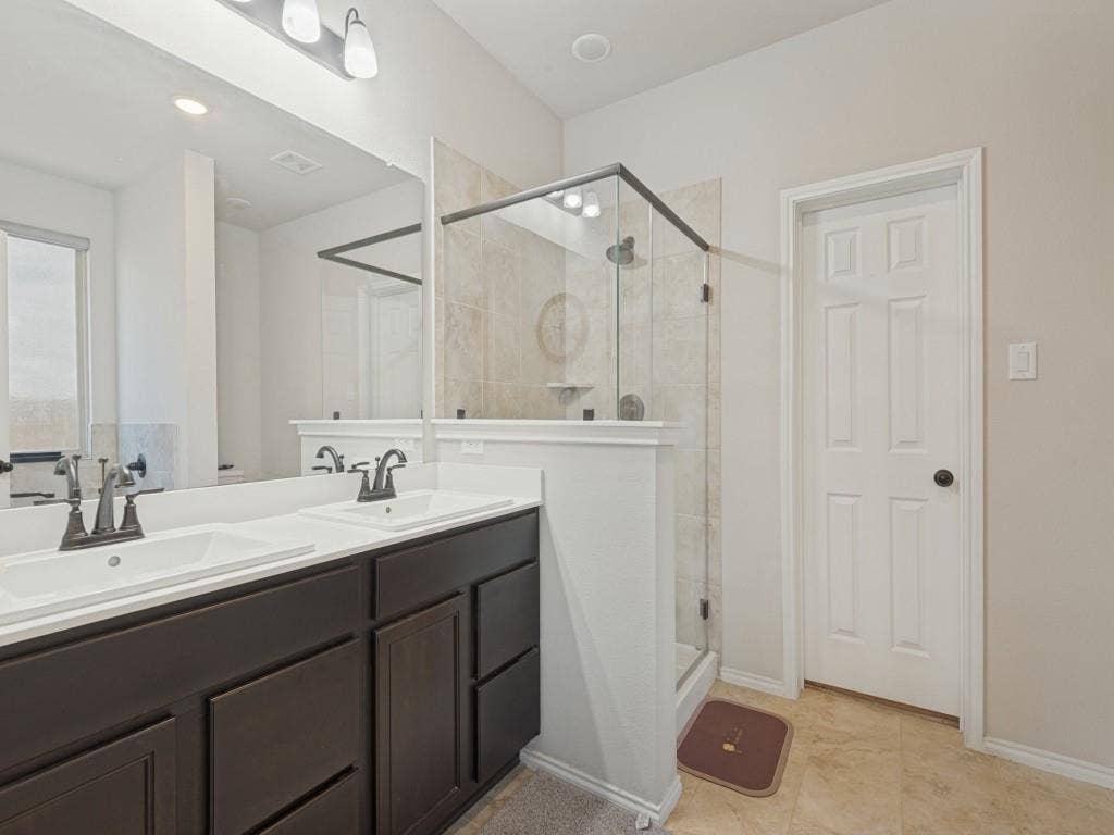 3825 S Courtney Court, Heartland, TX 75126 Spa-inspired primary bathroom featuring a dark-finish vanity with dual sinks, white quartz countertops, and polished chrome faucetry