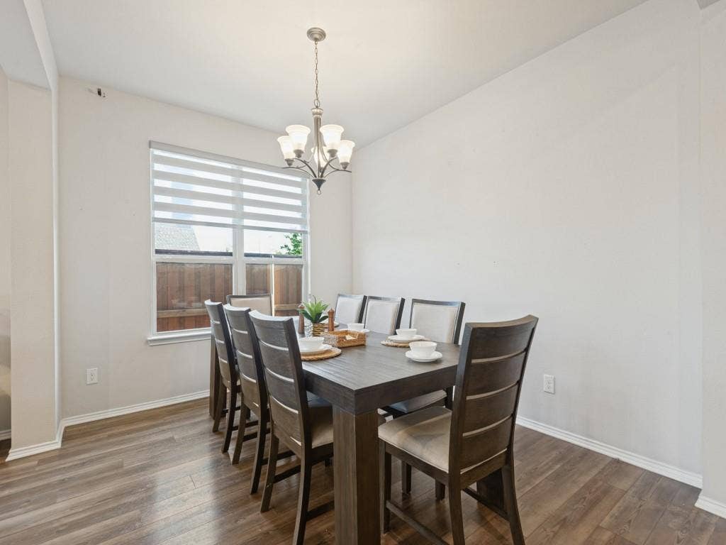 3825 S Courtney Court, Heartland, TX 75126 Dining area featuring wood-finish flooring, a contemporary chandelier, and a window with horizontal blinds