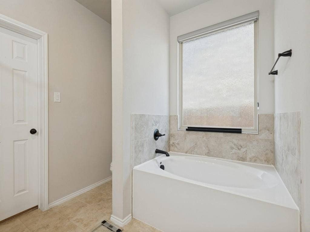 3825 S Courtney Court, Heartland, TX 75126 Soaking tub with black fixtures, tiled surround, and a frosted window