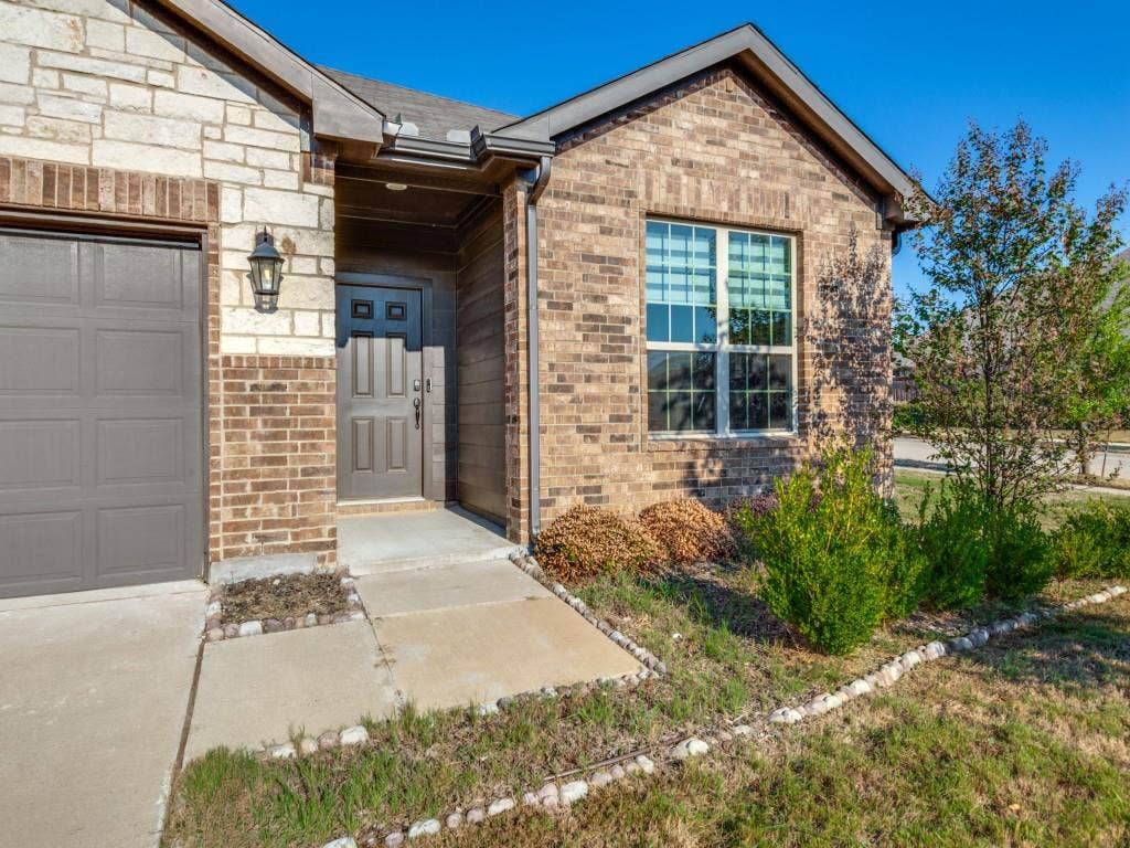 3825 S Courtney Court, Heartland, TX 75126 Charming brick residence featuring a covered entry portico, dual-pane windows with black frames, and an attached single-car garage