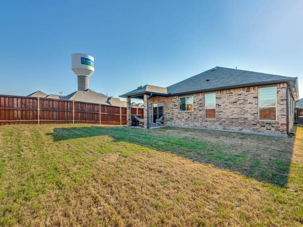 3825 S Courtney Court, Heartland, TX 75126 Brick exterior with multiple windows, covered patio, and a dark shingle roof