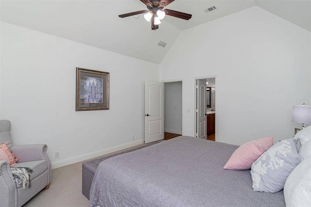 Vaulted ceiling with a ceiling fan, white paneled doors, and light-colored carpet flooring