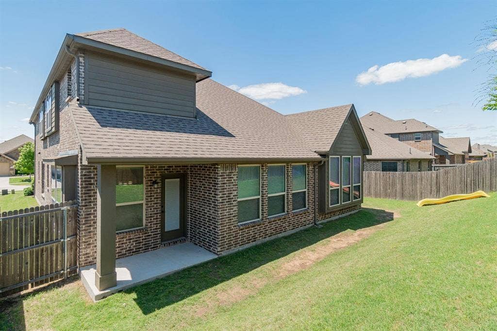 Brick exterior with gabled roofline, concrete patio, covered porch, and a fenced backyard