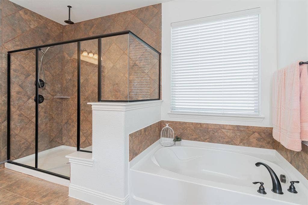 Walk-in shower with black-framed glass enclosure, built-in shower shelf, and ceiling-mounted rain shower head