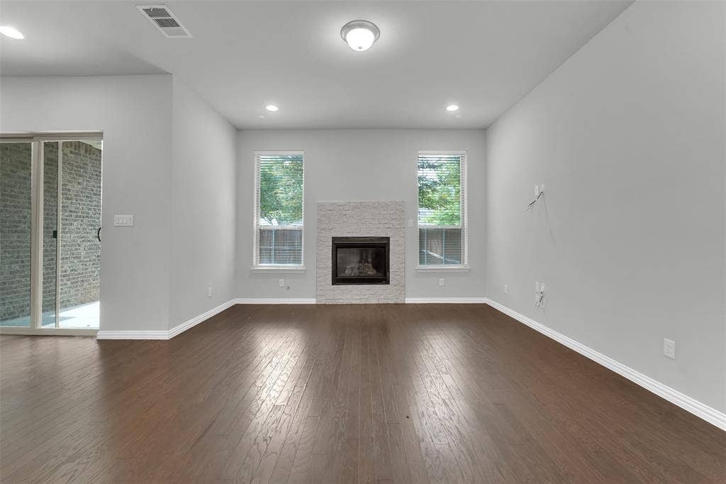 8266 Primrose Way, Dallas, TX 75252 Wood-finish flooring, recessed lighting, and a fireplace with a stacked stone surround