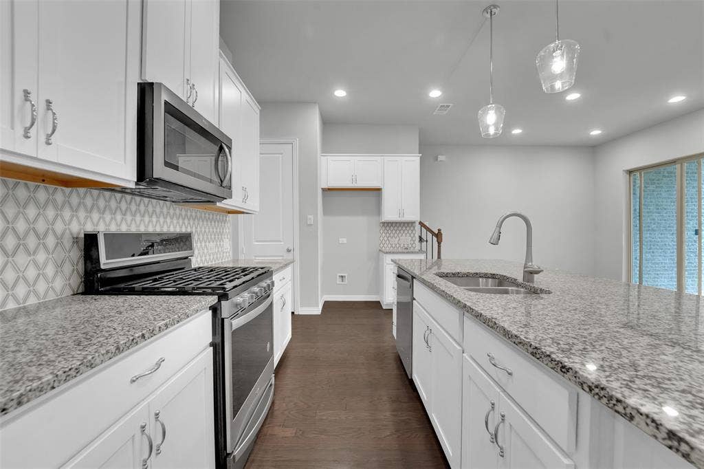 8266 Primrose Way, Dallas, TX 75252 Contemporary kitchen featuring white cabinetry, stainless steel appliances, granite countertops, and a patterned tile backsplash
