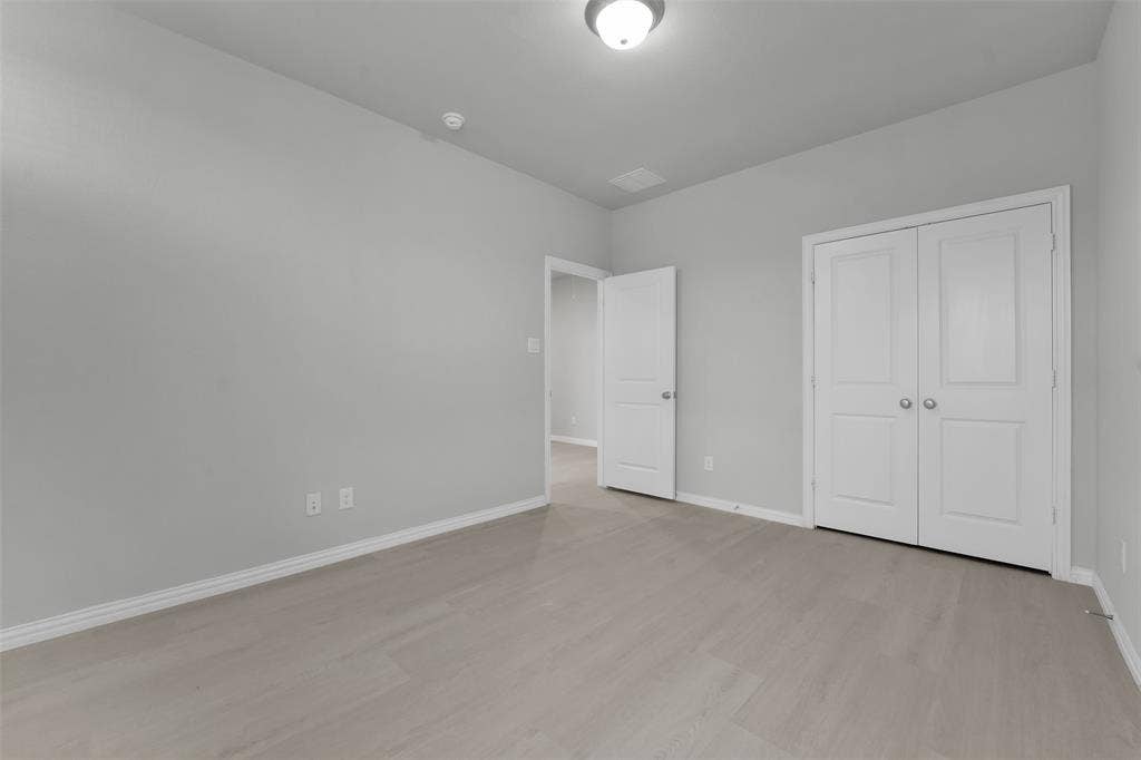 8266 Primrose Way, Dallas, TX 75252 Light wood-finish flooring, white walls, white trim, and white bi-fold doors