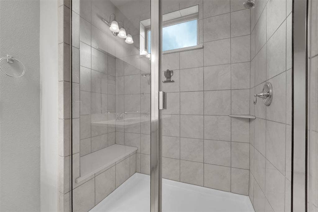 8266 Primrose Way, Dallas, TX 75252 Glass-enclosed shower with tile surround, built-in bench, and chrome fixtures
