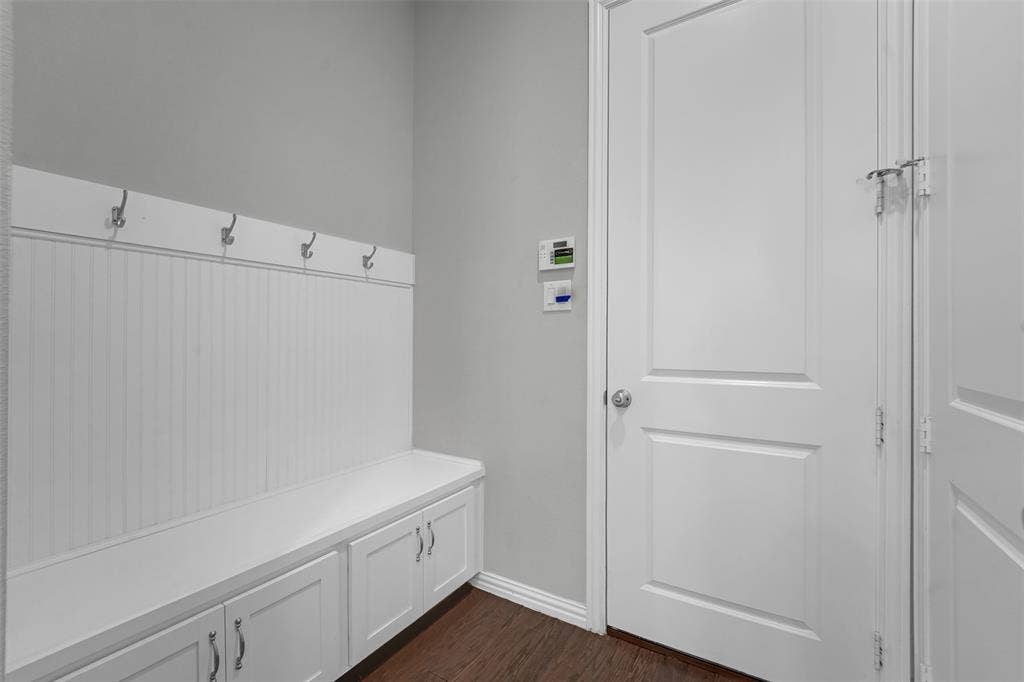 8266 Primrose Way, Dallas, TX 75252 Built-in storage bench with cabinet doors, beadboard paneling, and wall-mounted hooks