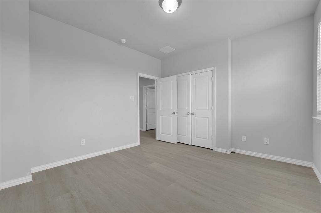 8266 Primrose Way, Dallas, TX 75252 Wood-finish flooring, white bifold closet doors, and a ceiling-mounted light fixture