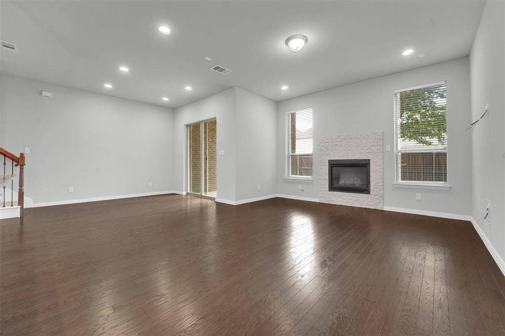 8266 Primrose Way, Dallas, TX 75252 Spacious living area featuring wood-finish flooring, recessed lighting, and a fireplace with a textured stone surround