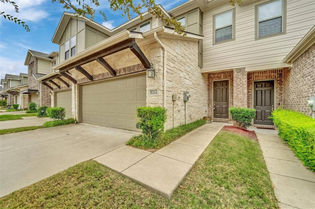 8266 Primrose Way, Dallas, TX 75252 Exterior featuring stone and brick accents, an attached two-car garage with a pergola-style awning, and an entry with a dark panel door