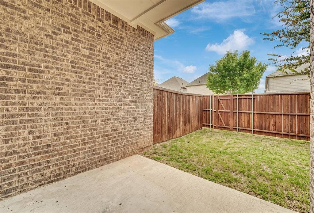 8266 Primrose Way, Dallas, TX 75252 Private fenced backyard featuring a concrete patio and a brick exterior wall