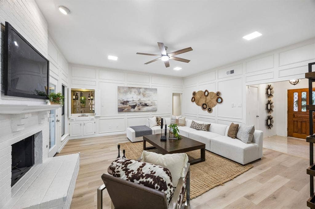 4540 New Orleans Drive, Plano, TX 75093 Spacious living area featuring light wood-finish flooring, a white brick fireplace, and built-in wet bar with cabinetry