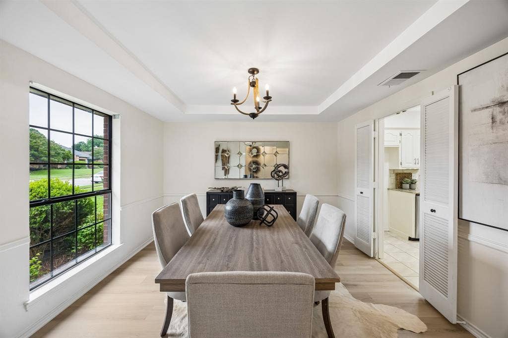 4540 New Orleans Drive, Plano, TX 75093 Tray ceiling, wood-finish flooring, wainscoting, black grid window, and a built-in chandelier