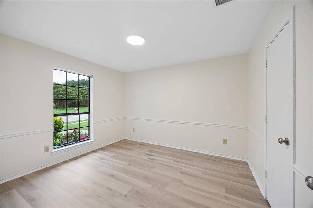 4540 New Orleans Drive, Plano, TX 75093 Recessed lighting and a skylight illuminate this space featuring wood-finish flooring, chair rail molding, and a grid-pattern window