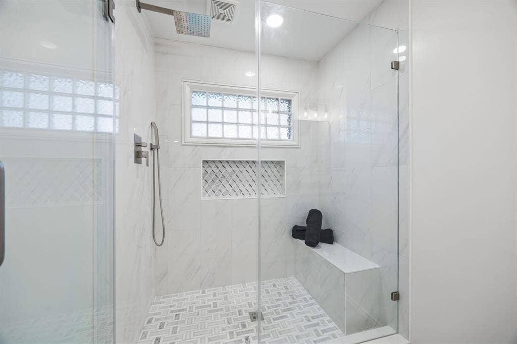 4540 New Orleans Drive, Plano, TX 75093 Glass-enclosed shower with a rainfall showerhead, handheld shower fixture, built-in bench, and tiled niche