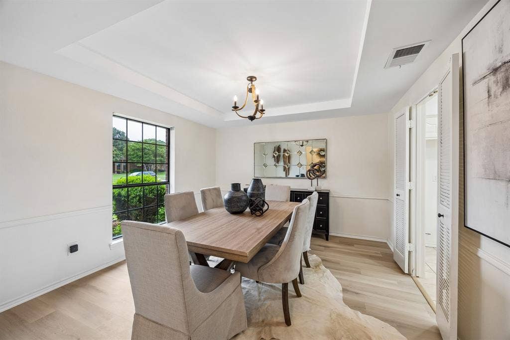4540 New Orleans Drive, Plano, TX 75093 Tray ceiling with a bronze-finish chandelier, wood-finish flooring, and wainscoting