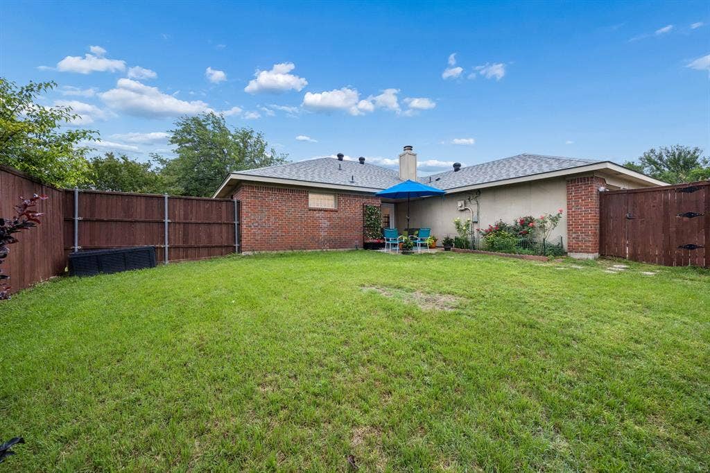 4540 New Orleans Drive, Plano, TX 75093 Expansive backyard featuring a lush lawn, solid wood fencing, and a brick exterior