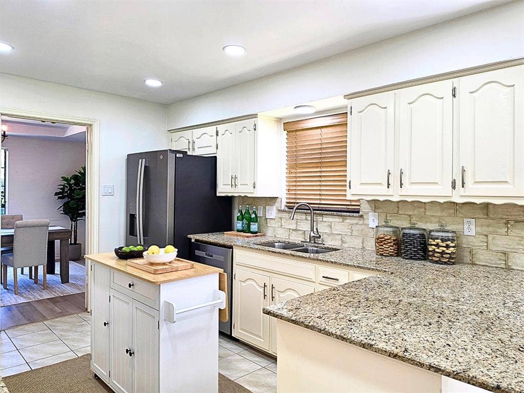 4540 New Orleans Drive, Plano, TX 75093 Kitchen featuring granite countertops, a tile backsplash, light-toned cabinetry, and stainless steel appliances