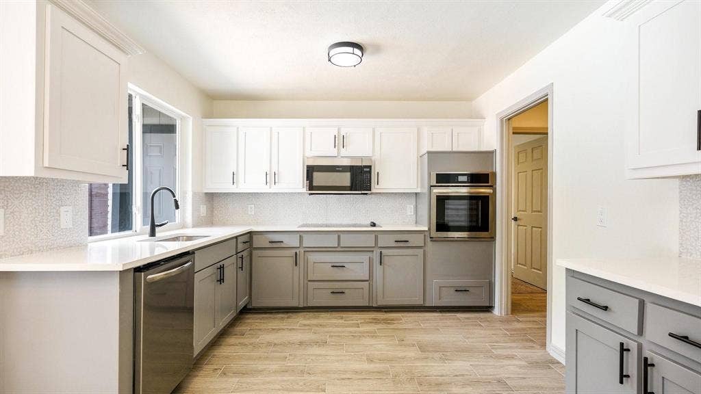 2616 Ellis Court, Plano, TX 75075 Modern kitchen featuring two-tone cabinetry, stainless steel appliances, white countertops, a mosaic tile backsplash, and wood-finish flooring