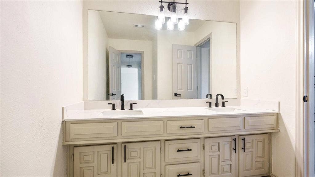 2616 Ellis Court, Plano, TX 75075 Dual vanity with white countertop, undermount sinks, matte black faucets, and coordinating cabinet hardware