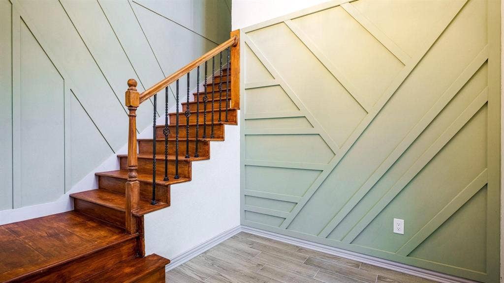 2616 Ellis Court, Plano, TX 75075 Hardwood staircase with decorative wrought iron balusters, custom geometric accent wall paneling, and wood-finish tile flooring