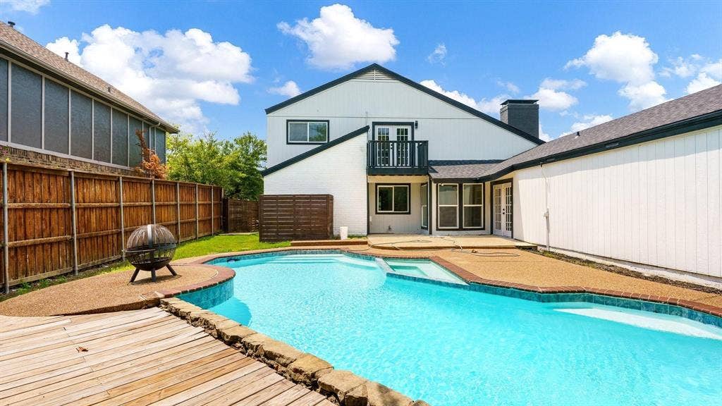 2616 Ellis Court, Plano, TX 75075 Outdoor living space featuring a swimming pool with integrated spa, wood decking, and an elevated balcony with railing