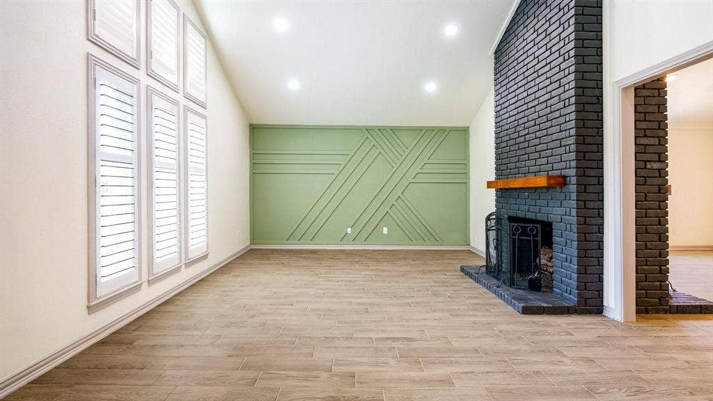 2616 Ellis Court, Plano, TX 75075 Vaulted ceiling with recessed lighting, wood-finish flooring, accent wall with decorative molding, and a black brick fireplace with a wood mantel