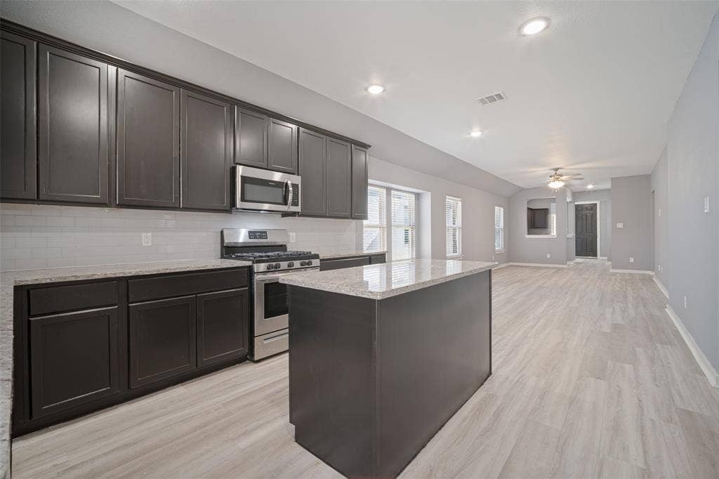 2324 Neff Lane, Forney, TX 75126 Kitchen featuring dark cabinetry, stone-finish countertops, stainless steel appliances, a subway tile backsplash, and wood-finish flooring