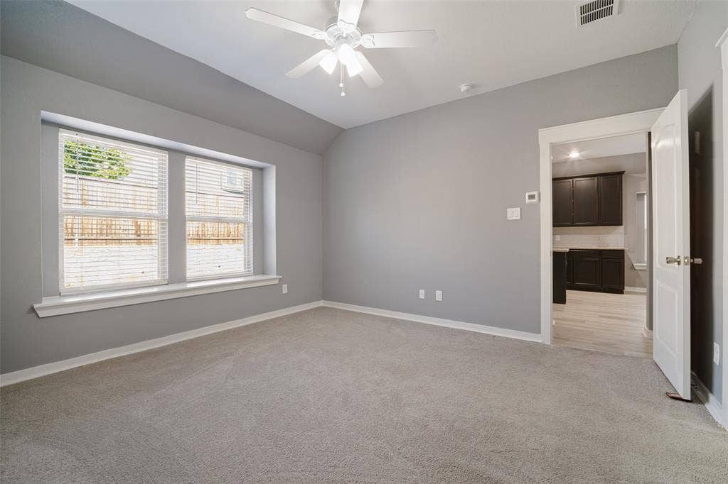 2324 Neff Lane, Forney, TX 75126 Neutral-toned room featuring a vaulted ceiling, bay window with sill, carpeted flooring, and a ceiling-mounted fan with light fixture