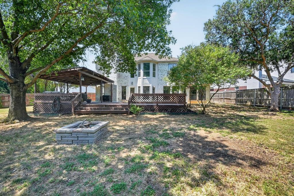 519 Fox Creek Court, Denton, TX 76209 Expansive backyard featuring a multi-level wood deck, a covered patio area, and a built-in stone fire pit